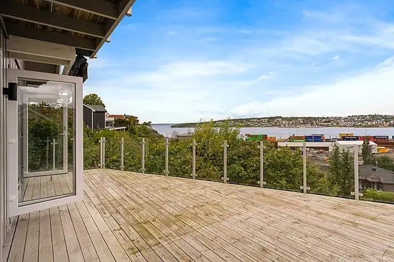 Stor foldedør åpner opp til en solrik terrasse med utsikt mot Oslofjorden