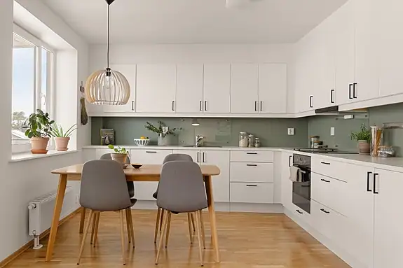 Pent vinkelkjøkken med glatte hvite froner og laminert hvit benkeplate