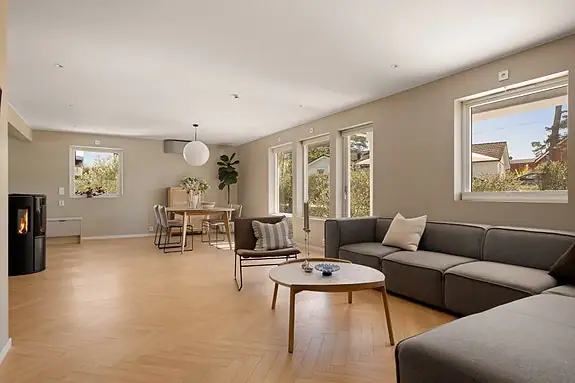 Delikate jordtoner, store vindusflater og lune materialvalg gir boligen et elegant uttrykk