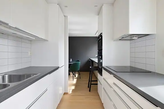 Ikeakjøkken fra 2014 med glatte hvite fronter, mørk laminert benkeplate og fliser mellom kjøkkenbenk og overskap