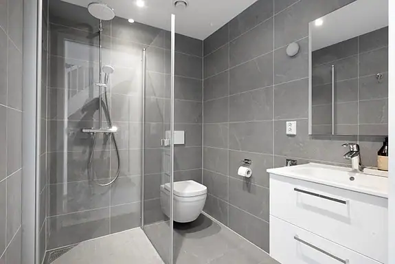 Moderne og delikat bad i første etasje med dusjhjørne, baderomsinnredning, veggmontert wc og speil med integrert belysning