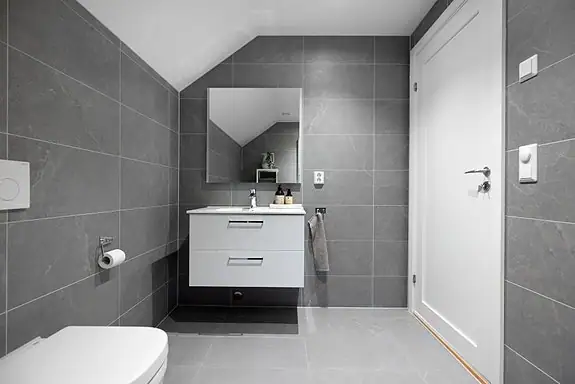 Badet i 2. etasje har samme moderne uttrykk og materialvalg som badet i 1. etasje med flislagte overflater og varmekabler i gulv