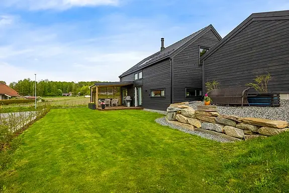 Tomten er opparbeidet med plen, hekk, grus og diverse beplantning