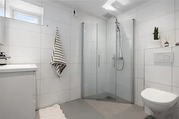 Pent og tidløst bad med flislagte overflater og varmekabler i gulv