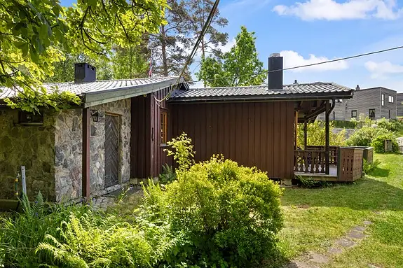 Hytten har et sjarmerende eksteriør med kombinasjon av treverk og naturstein