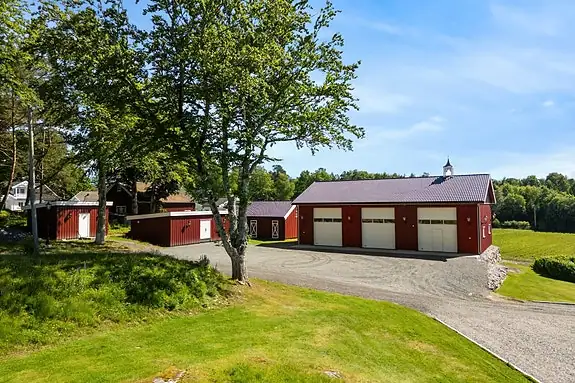 Her får du den ekte gårdsfølelsen - med røde driftsbygninger som rammer inn eiendommen