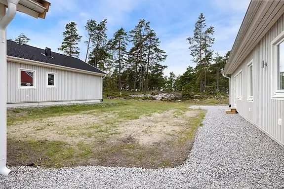 Uteplassen ligger solrikt og skjermet til, med en lun atmosfære og en vakker skogkledd bakgrunn som skaper en harmonisk ramme rundt utelivet