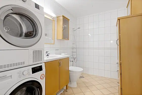 Flislagt bad med dusjhjørne, WC, baderomsinnredning, varmekabler og opplegg for vaskemaskin. Badet er fra byggeåret, og oppussing må påregnes