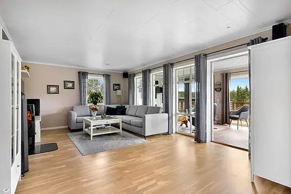 Lys og romslig stue med peis som naturlig samlingspunkt