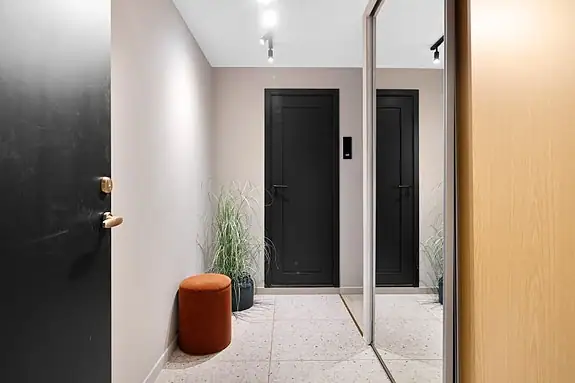 Innbydende og flislagt entre med praktisk skyvedørsgarderobe
