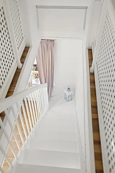 Den hvitmalte tretrappen forbinder stuen med det innredede loftet. Loftets godkjenning til varig opphold er ikke dokumentert.