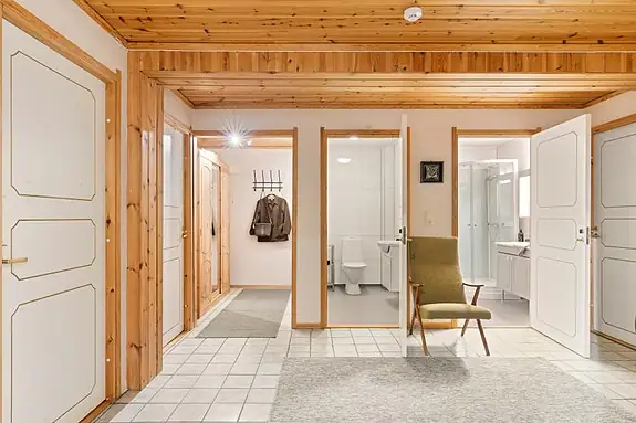 Hallen fungerer som et naturlig knutepunkt i etasjen, med adkomst til flere av boligens rom