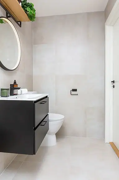 Badet er utstyrt med gulvstående toalett, baderomsinnredning, speil med integrert belysning, dusjhjørne og opplegg for vaskemaskin