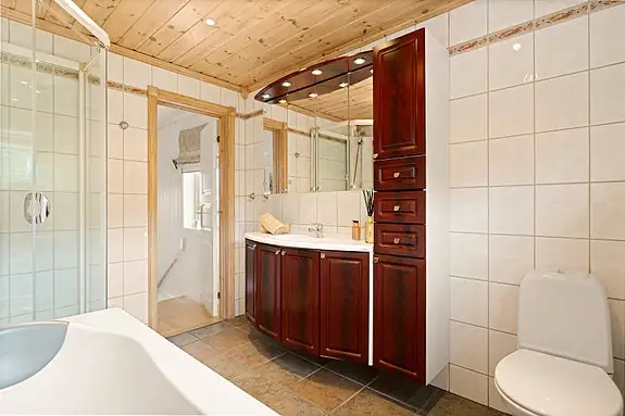 Rommet er innredet med badekar, dusjkabinett, gulvstående wc og baderomsinnredning